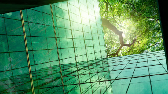 Sustainble green building. Eco-friendly building in modern city. ESG. Sustainable glass office building with green tree. Office with green environment. Corporate sustainability. Net zero emission.
